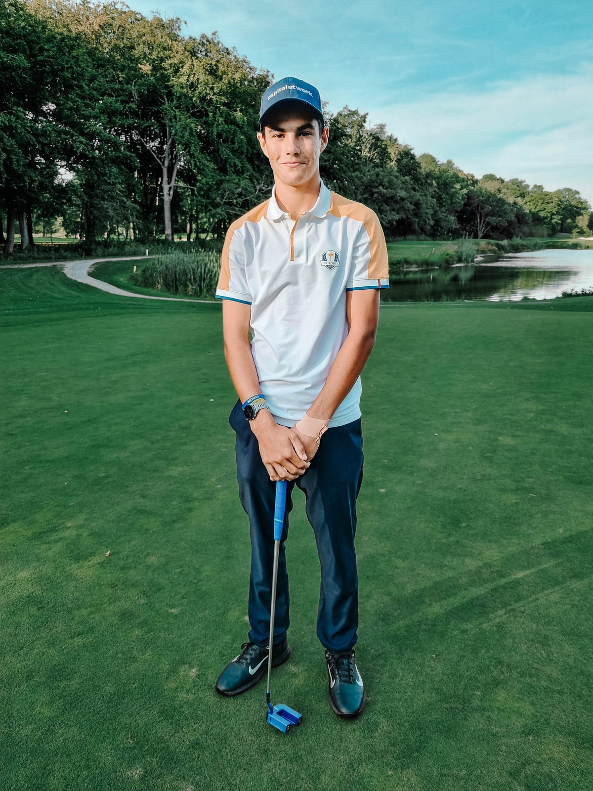 Young golfer with myvicto M-Serie blue putter on putting green with lake
