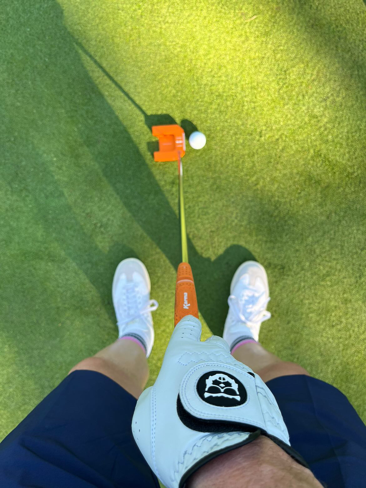 POV view of hands gripping myvicto E-Serie orange putter at address